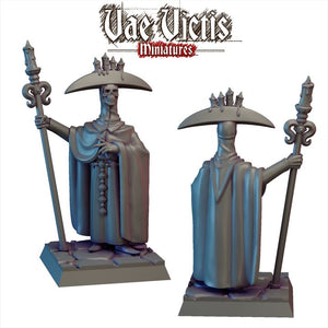 two figurines of a person wearing a hat and holding a staff, standing on a platform.