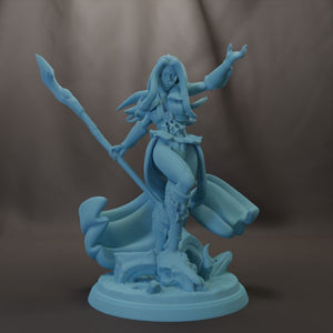 A figurine of a female character with long hair, wielding a staff and standing on a rock formation.