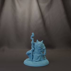 A small figurine of a cat holding a staff and wearing a robe, sitting on a base.