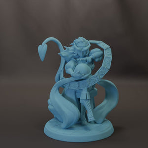 A blue figurine of a fantastical creature with a large head and long, flowing body, holding a round object in its hands.