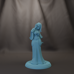 A light blue figurine of a woman with long hair and a flowing dress stands on a circular base against a dark background.