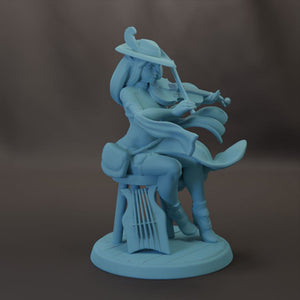 A light blue figurine of a woman playing a musical instrument, such as a violin or guitar, while wearing a hat and holding a bag.
