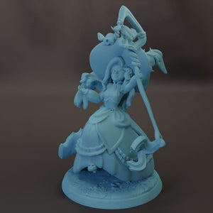 A figurine of a woman with a large hat and a long staff, standing on a base with a skull and other elements.