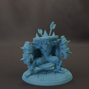 A light blue figurine of a character with a crown-like headpiece and various weapons, sitting on a platform.