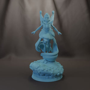 A blue figurine of a fairy or magical creature with wings and a flowing dress stands on a textured base against a dark background.