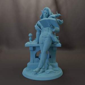 A light blue figurine depicting a woman sitting at a desk, reading a book and holding a cup.