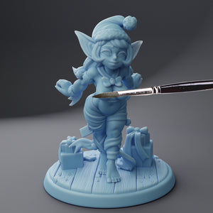 a blue figurine holding a paintbrush on top of a table